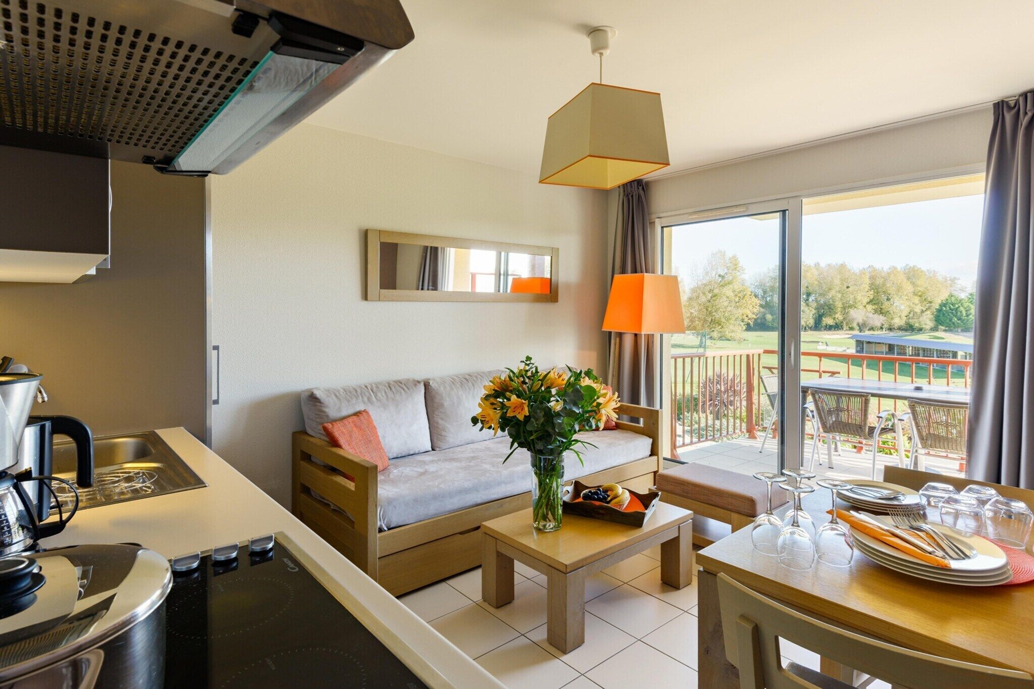 A modern kitchen with a stove, sink, and dining area with a table set for two.