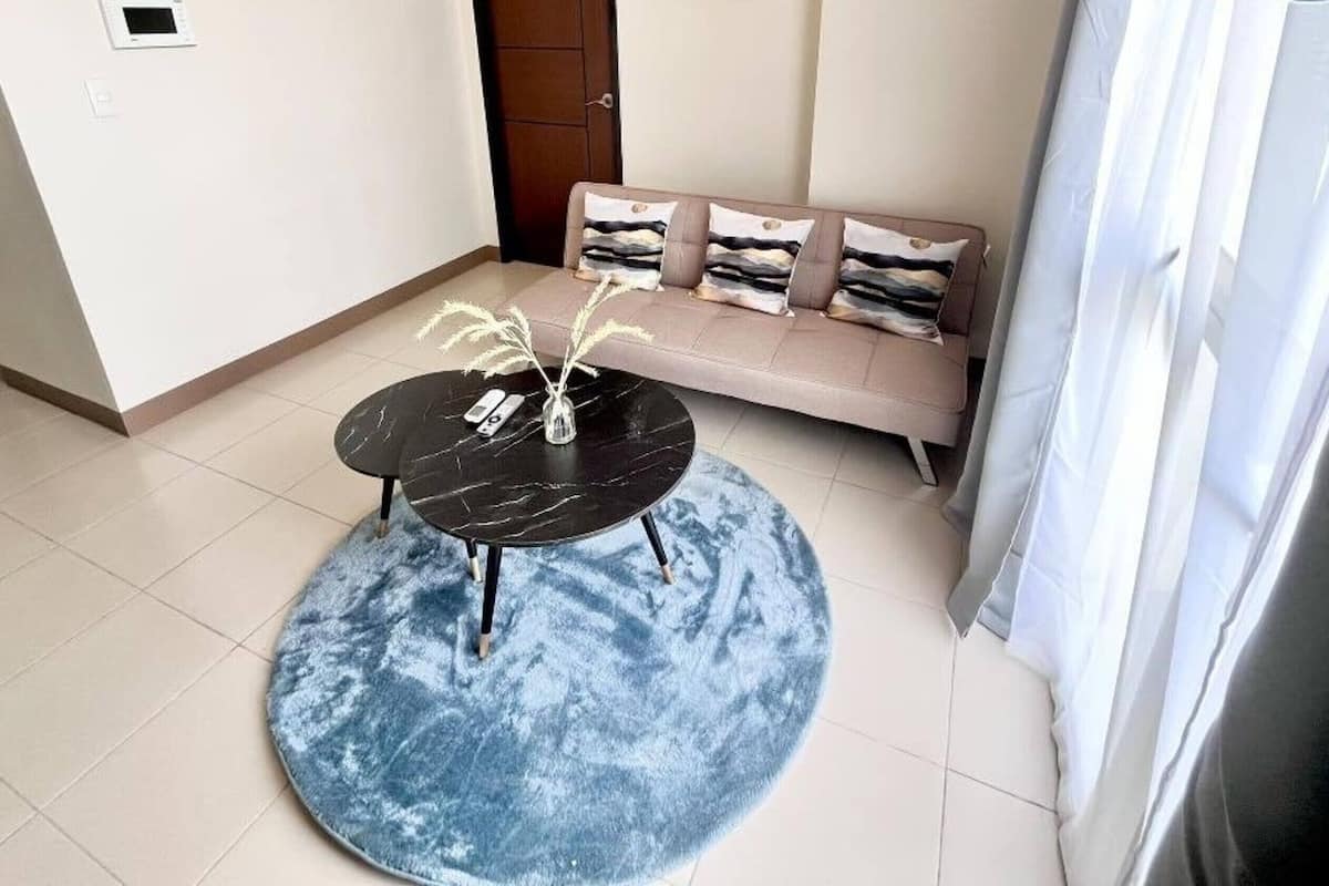 Una sala de estar moderna con un sofá, una mesita redonda y una alfombra azul.