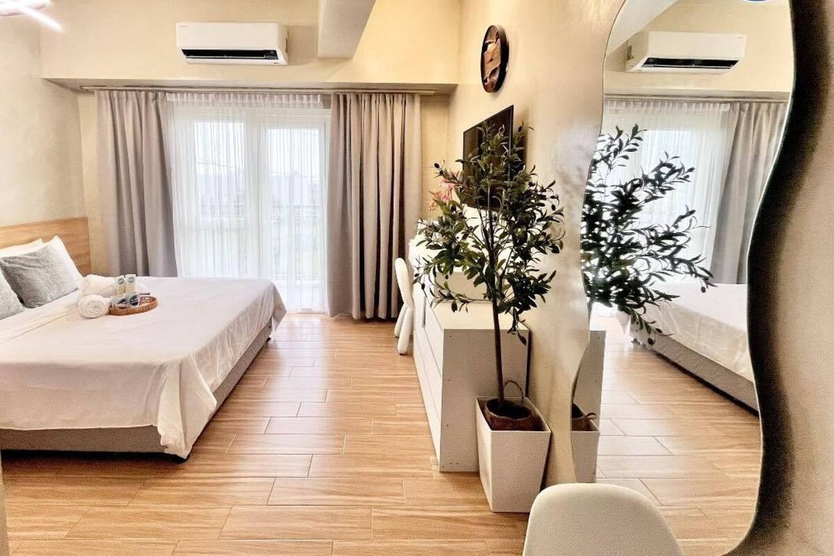Una habitación de hotel con una cama, una mesita de noche con una planta y una silla.