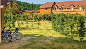 Un patio con bicicletas, un edificio de techo rojo y una ladera verde al fondo.