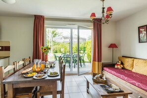 A dining area with a table set for a meal, a sofa with a teddy bear, and a sliding glass door leading to an outdoor patio. - Duplex Escape in the Heart of Dordogne (Bergerac)