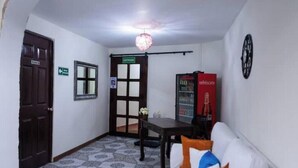 A hallway with a door, a window, a table with a bottle, a couch, and a refrigerator. - Apartment in San Salvador (San Salvador)