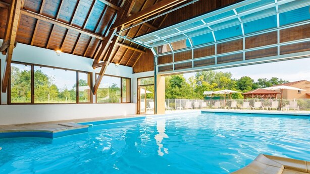 Une piscine intérieure dotée d’un plafond en bois et de grandes fenêtres.