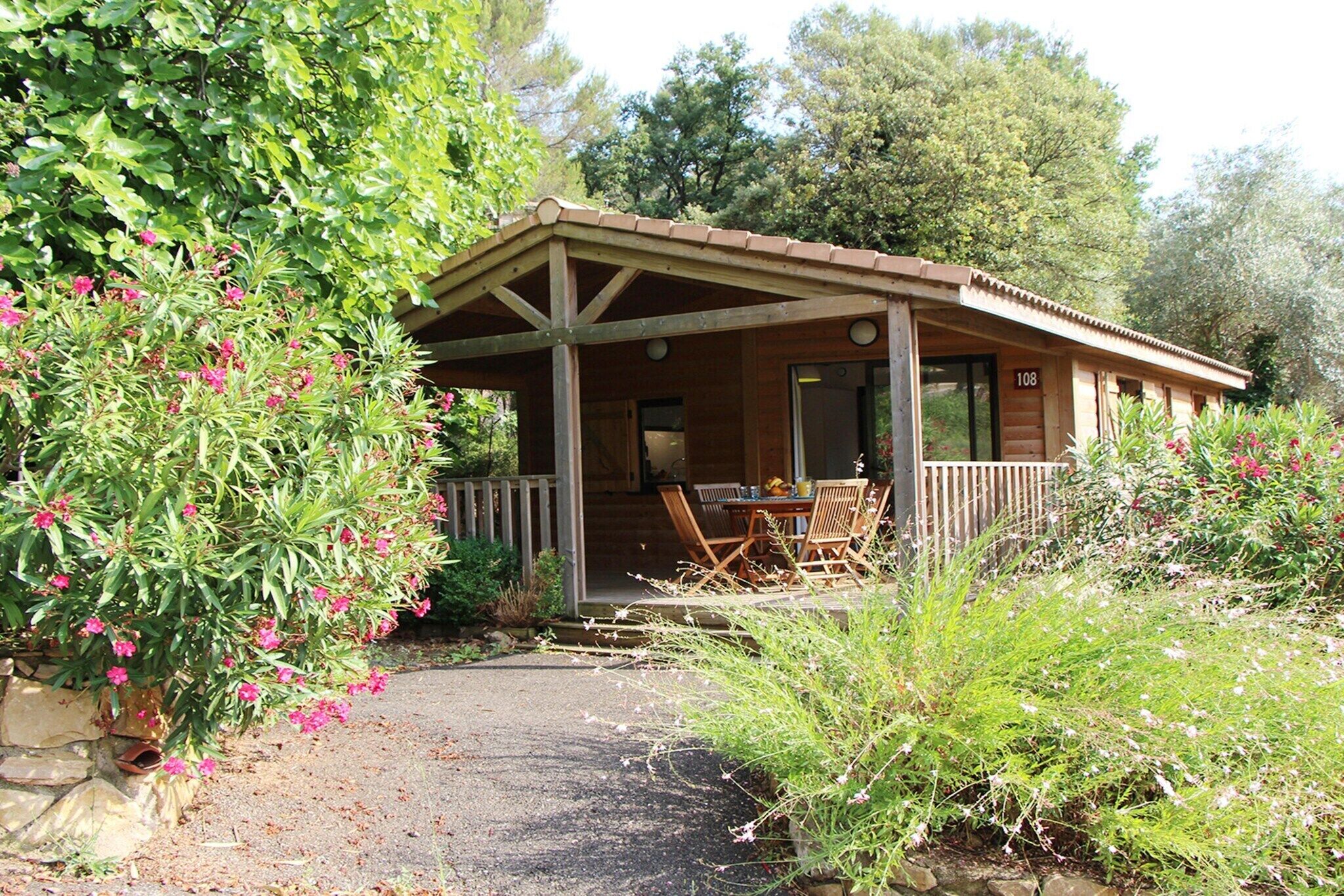 Une cabane en bois avec un porche, une table et des chaises, et le numéro « 108 » sur la porte.