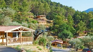 Une cabane en bois dotée d’un porche, entourée d’arbres et de collines.