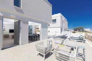 Eine moderne Außenpatio mit Korbmöbeln, einem Essbereich und freiem Blick auf die umliegenden Gebäude.