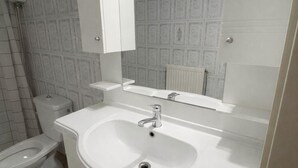 A bathroom with a white sink, a mirror, and a toilet. - Casa Katerina studio apartment (Chania)
