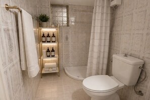 A bathroom with a toilet, a shower, and a shelf with toiletries. - Casa Katerina studio apartment (Chania)
