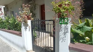 A gated entrance with a white wall, a black gate, and potted plants. - Casa Katerina studio apartment (Chania)