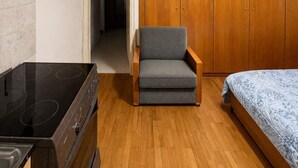 A compact room with a kitchenette, a single bed, a chair, and a wardrobe. - Casa Katerina studio apartment (Chania)