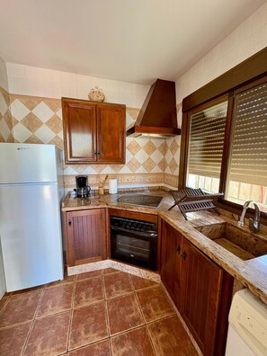 Eine kleine Küche mit Kühlschrank, Herd, Spüle und Holzsäschränken.