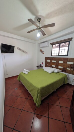 A bedroom with a bed, a ceiling fan, a TV, and a window. - Apartment 101 in Villa Stahl, Colonia Escalon (San Salvador)