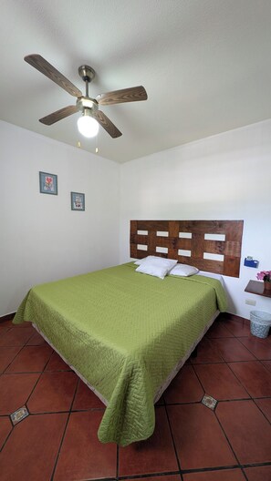 Ein Schlafzimmer mit einem Bett, einem Deckenventilator und einem an der Wand befestigten Regal.