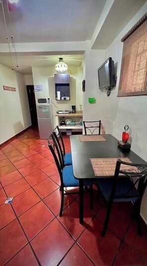 A dining area with a table, chairs, and a television on the wall. - 101 Apartment in Villa Stahl, Colonia Escalon (San Salvador)