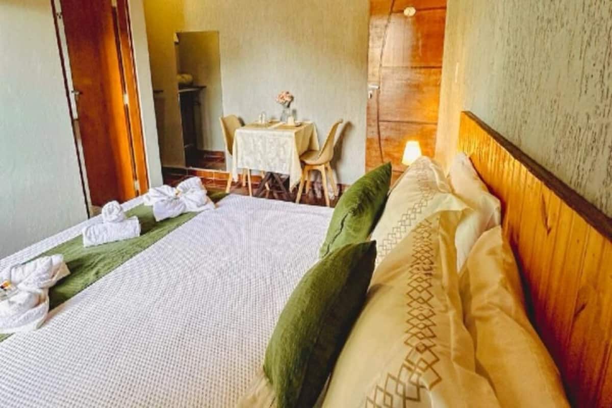 A neatly made bed with a green pillow, a white blanket, and a wooden headboard.