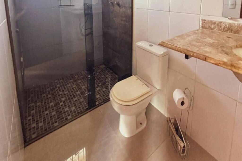 Un baño con inodoro, ducha y un perchero para toallas.