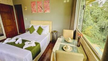 A hotel room with two beds, a small table with tea set, a chair, and a window with a view of greenery.