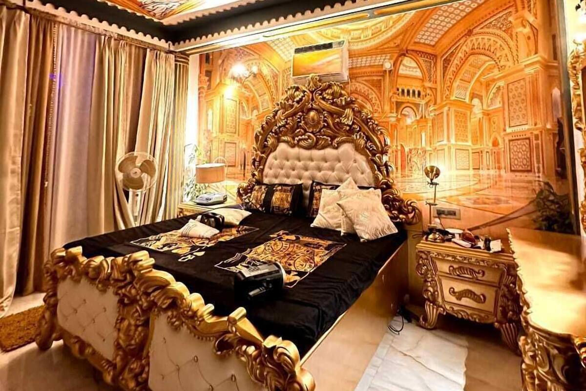 Un dormitorio lujoso con una cama grande, elaborados detalles de decoración en el techo y diseños detallados en las paredes.
