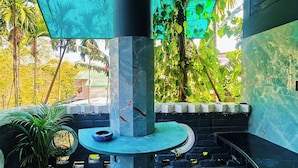 A balcony with a patterned floor, a round table, and a potted plant.