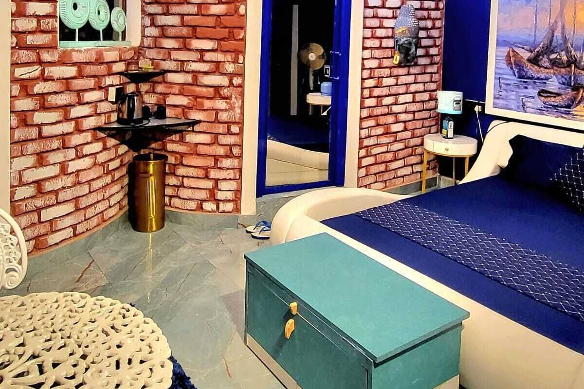Una habitación con pared de ladrillo, una cama, un escritorio, una silla y un ventilador de techo.