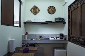 Une cuisine compacte équipée d’un four à micro-ondes, d’un grille-pain et d’un évier. Un tableau décoratif est accroché au mur, au-dessus du plan de travail.