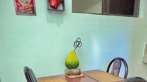 A dining area with a table, chairs, a decorative vase, and a wall with a coffee sign. - 103 Apartment in Villa Stahl, Colonia Escalon (San Salvador)