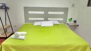 A single-bed room with a green bedspread, white pillows, and a headboard. - 103 Apartment in Villa Stahl, Colonia Escalon (San Salvador)