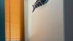 A corner seating area with a cushioned bench, a wall-mounted fish decoration, and a window with blinds. - Mersey Residence Koh Samui (Koh Samui)