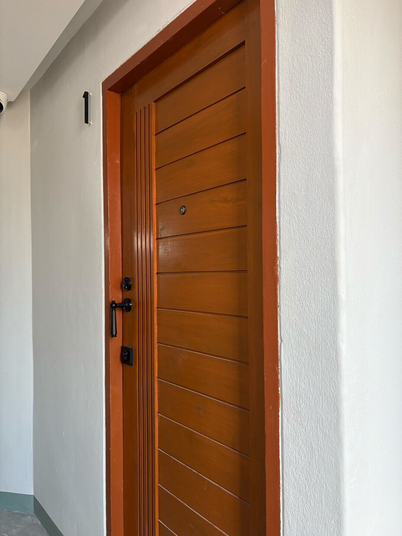A wooden door with a handle and a lock, white walls, and a small sign above the door.