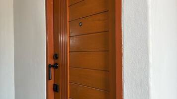 A wooden door with a handle and a lock, white walls, and a small sign above the door.