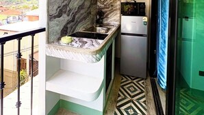 A compact kitchen with a marble backsplash, a built-in stove, and a refrigerator. - Mersey Residence Koh Samui (Koh Samui)