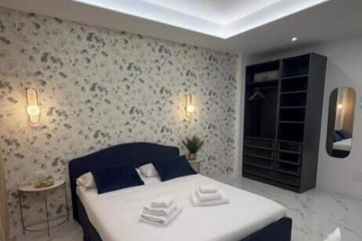 Un dormitorio moderno con cama, mesitas de noche, armario y luz en el techo.