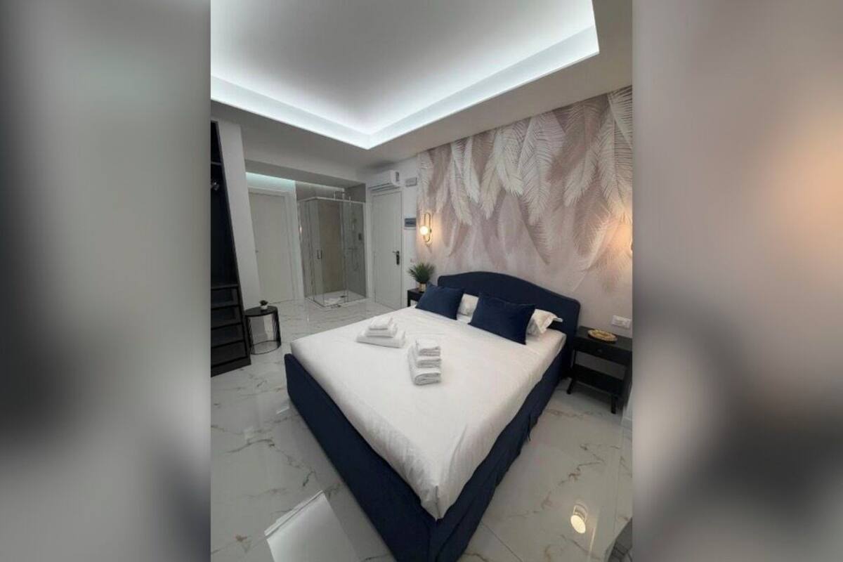 Un dormitorio moderno con una cama grande, un vestidor y un baño con ducha de vidrio.