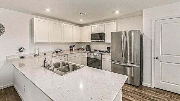 A modern kitchen with white cabinetry, stainless steel appliances, and a marble countertop. - Spacious 4BR Rental near Downtown Prescott (Prescott Valley)