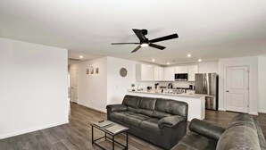A modern living room with a leather sofa, a coffee table, and a ceiling fan. - Spacious 4BR Rental near Downtown Prescott (Prescott Valley)