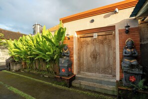 Un edificio tradicional con una puerta de madera, dos estatuas y un depósito de agua.