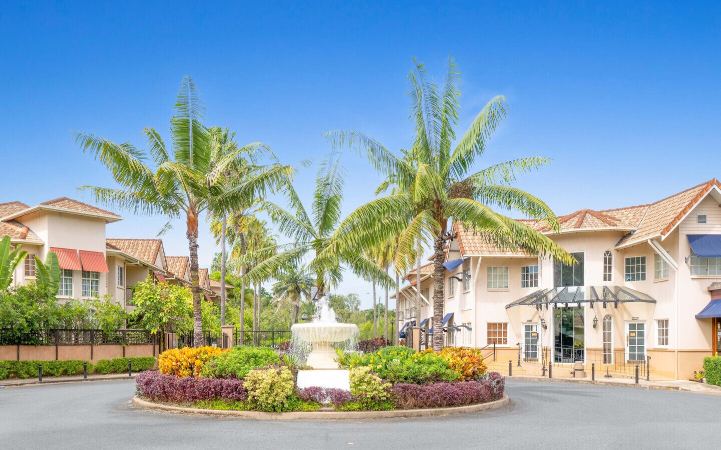 A residential area with houses, palm trees, and a central fountain.