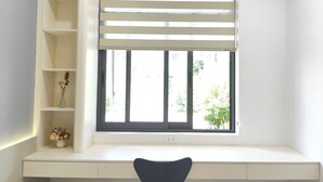 Um espaço de estudo com janela, escrivaninha e cadeira.