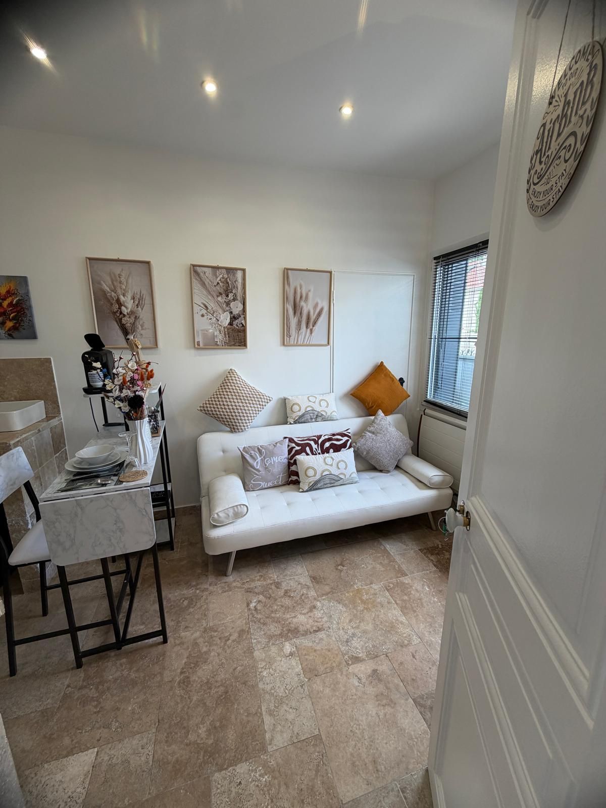Una sala de estar moderna con un sofá blanco, una mesa de comedor y obras de arte en las paredes.