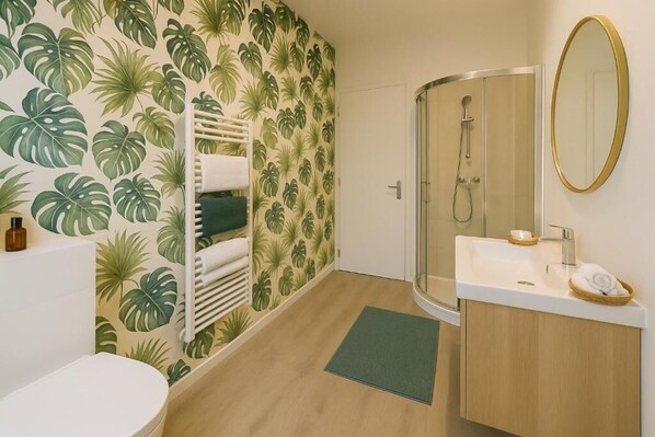 A bathroom with a shower, toilet, sink, and a towel rack.