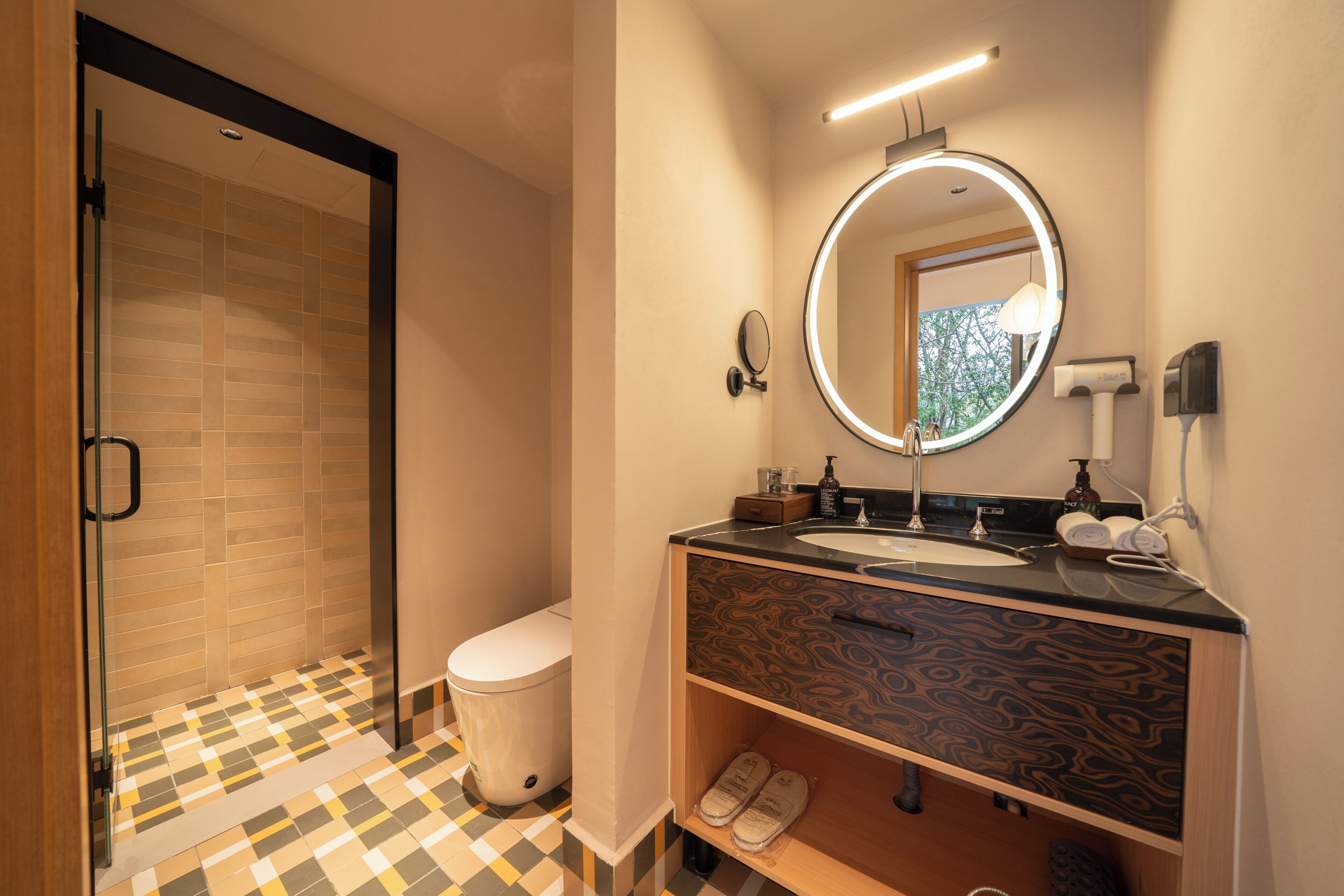 A modern bathroom with a glass shower, a toilet, a sink with a vanity, and a mirror with a light.
