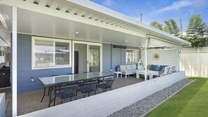 A modern outdoor patio with a dining table, chairs, and a seating area.