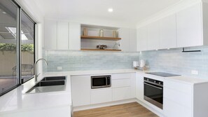 A modern kitchen with white cabinets, a stainless steel microwave, an oven, and a dishwasher.