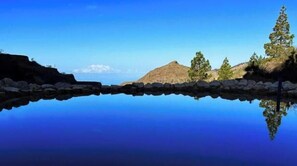 A calm lake with a clear reflection of a mountain and trees. - Jardines de Ifonche – 2-Bedroom Cave House in Tenerife (Adeje)