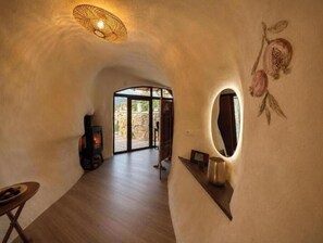 A cozy interior with a stone fireplace, a wooden table, and a unique wall design. - Jardines de Ifonche – 2-Bedroom Cave House in Tenerife (Adeje)