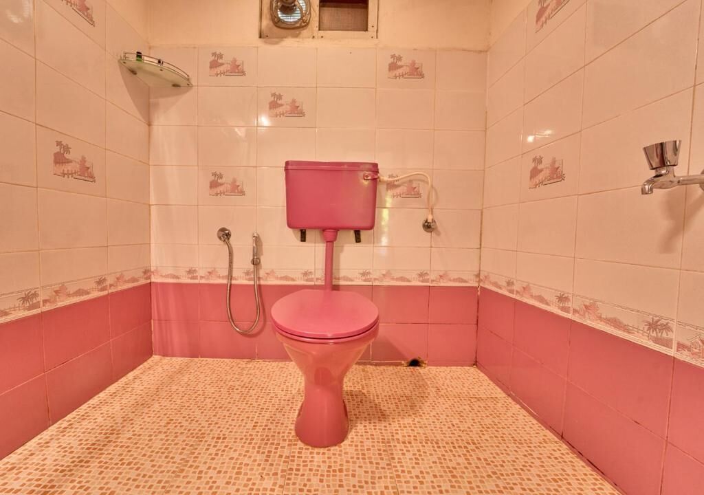 A bathroom with a pink toilet, a shower, and a small window.