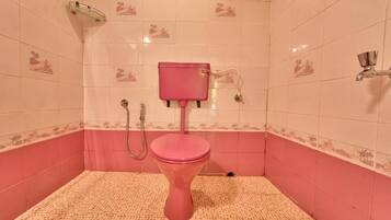 A bathroom with a pink toilet, a shower, and a small window.