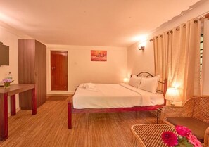 Una habitación de hotel con cama, mesita de noche, silla y un cuadro en la pared.