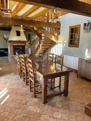 Ein Essbereich mit Holztisch und -stühlen, Kamin und Treppe.