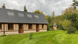 A traditional timber-framed house with a sloped roof, a small tower, and a well-maintained lawn. - Charming country cottage with fireplace near Rouen and the Normandy coast (Auzouville-l'Esneval)